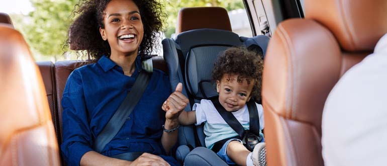a woman in a car smiling next to a child smiling in a car seat